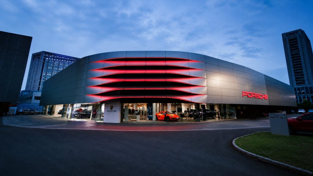 Modern Porsche dealership exterior with illuminated red architectural lighting showcasing luxury automotive retail design and next generation showroom experience
