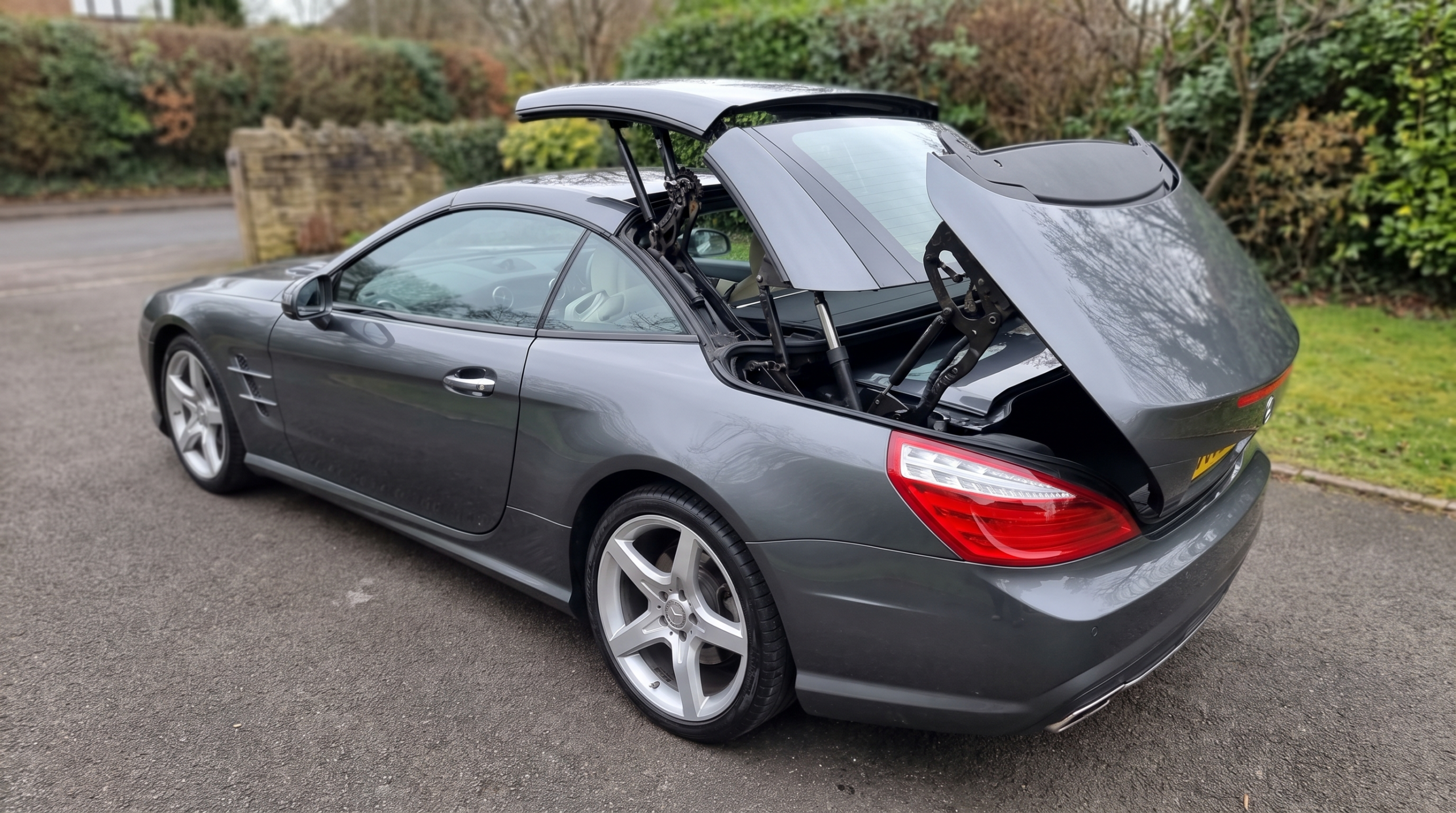Luxury convertible with its folding hardtop caught halfway through its cycle