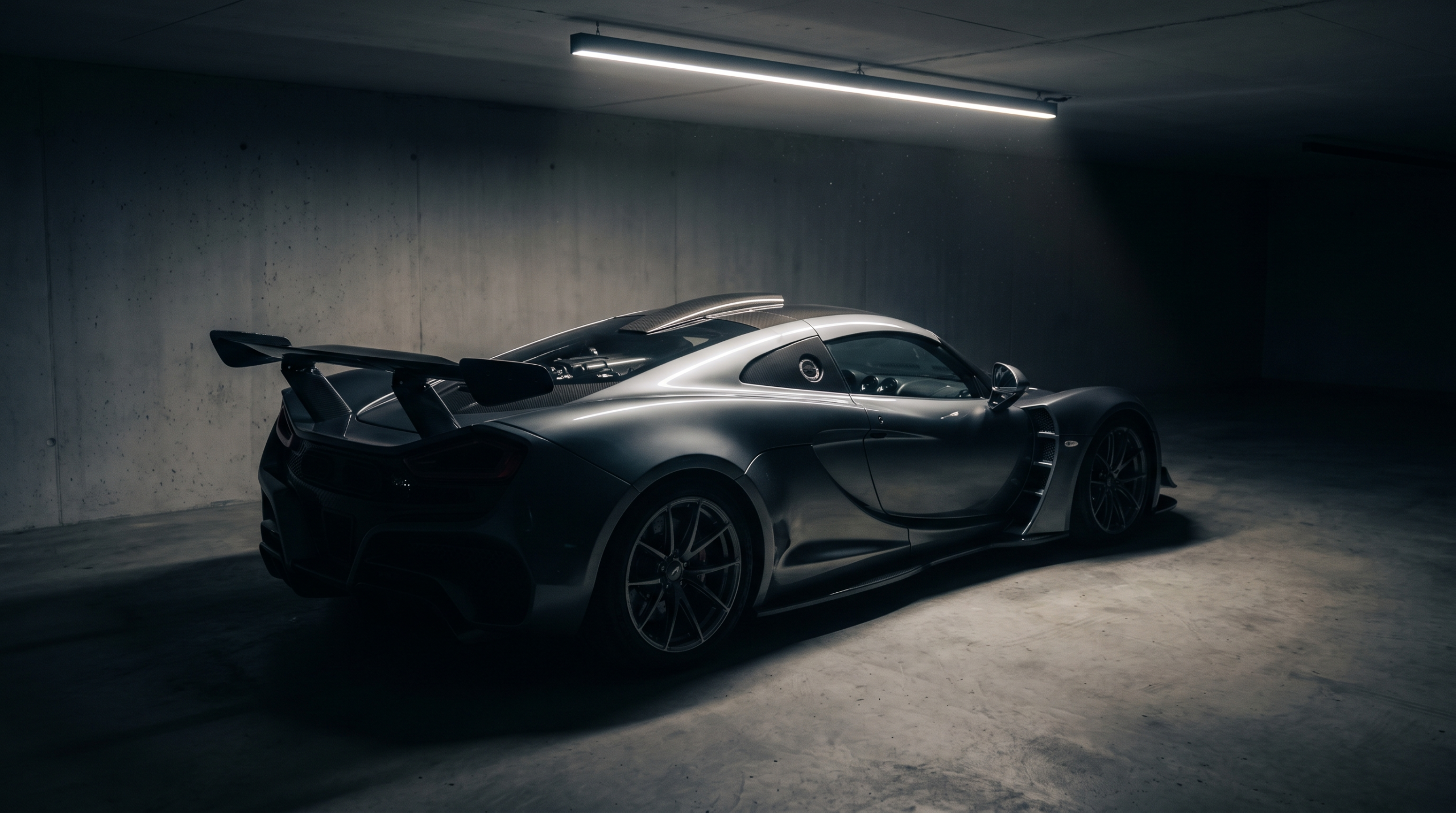 Exotic car values in the hybrid era: a dark grey hypercar with its active rear wing raised in a private garage