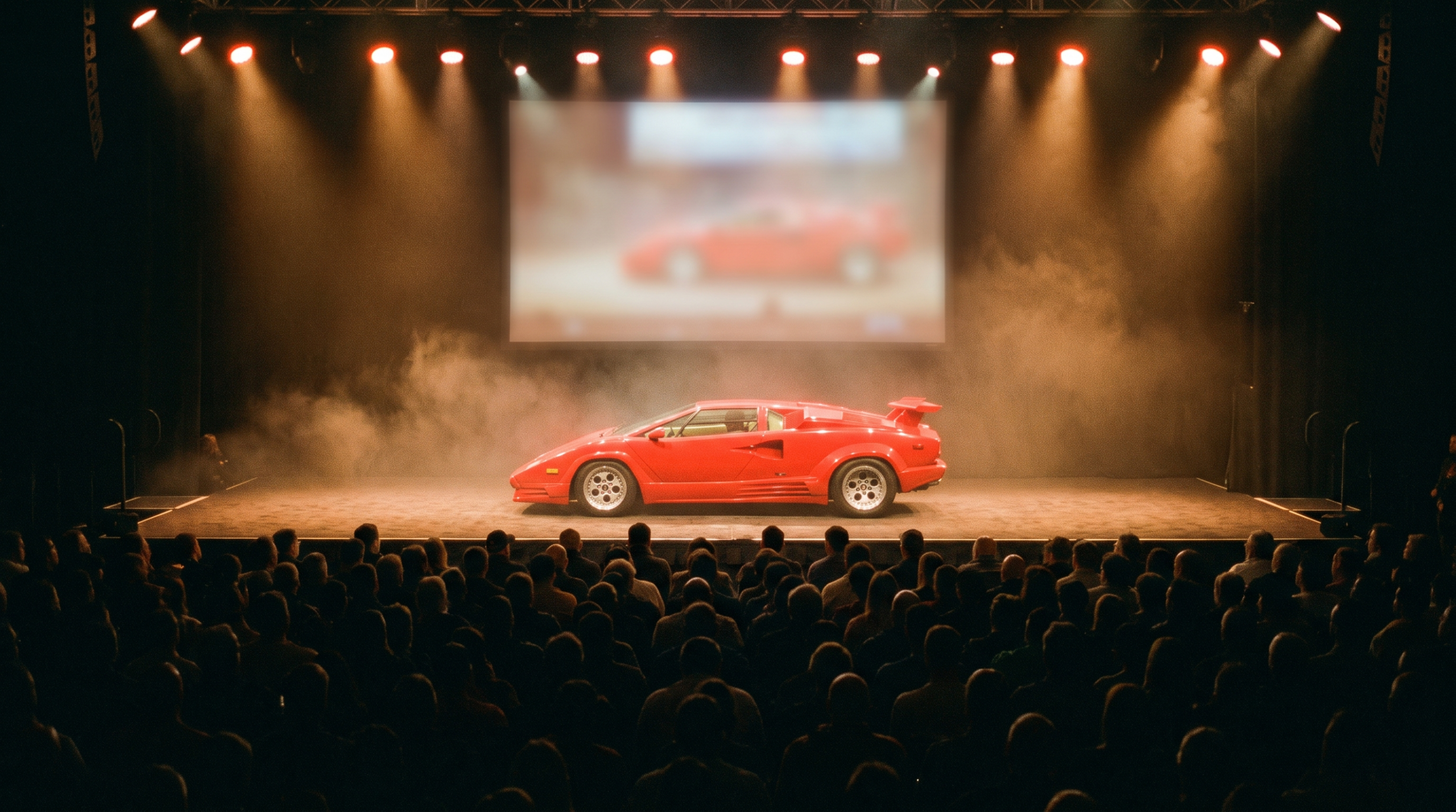 Red 1980s supercar on a rotating auction stage under theatrical lighting