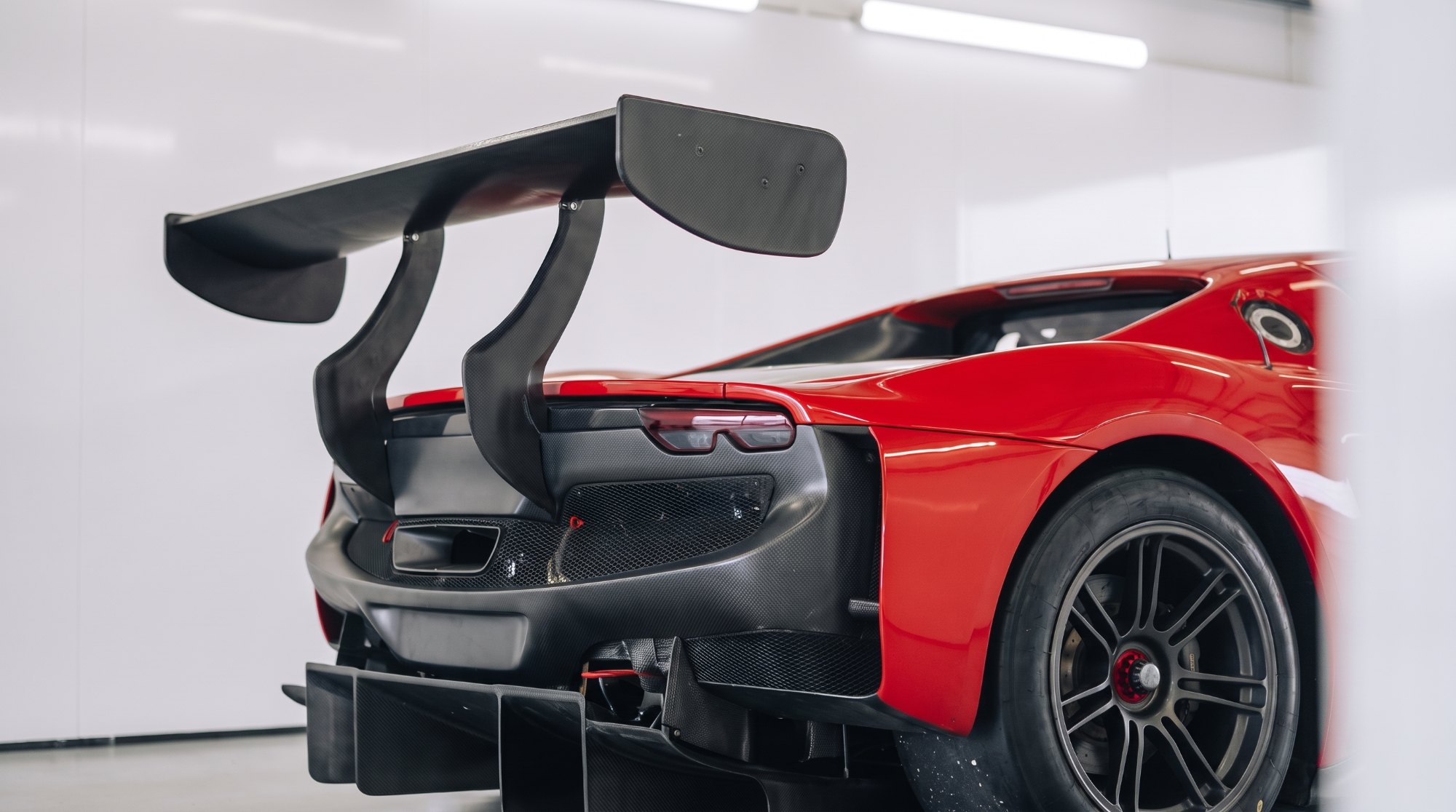 Carbon-fibre rear wing with swept endplates and an exposed diffuser on a red Ferrari 296-based track car