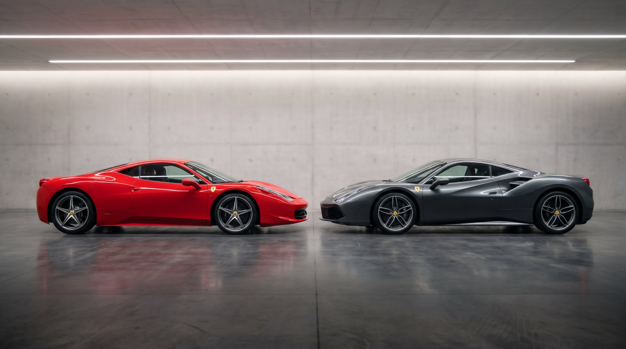 Red Ferrari 458 Italia and grey Ferrari 488 GTB parked nose to nose in a concrete studio